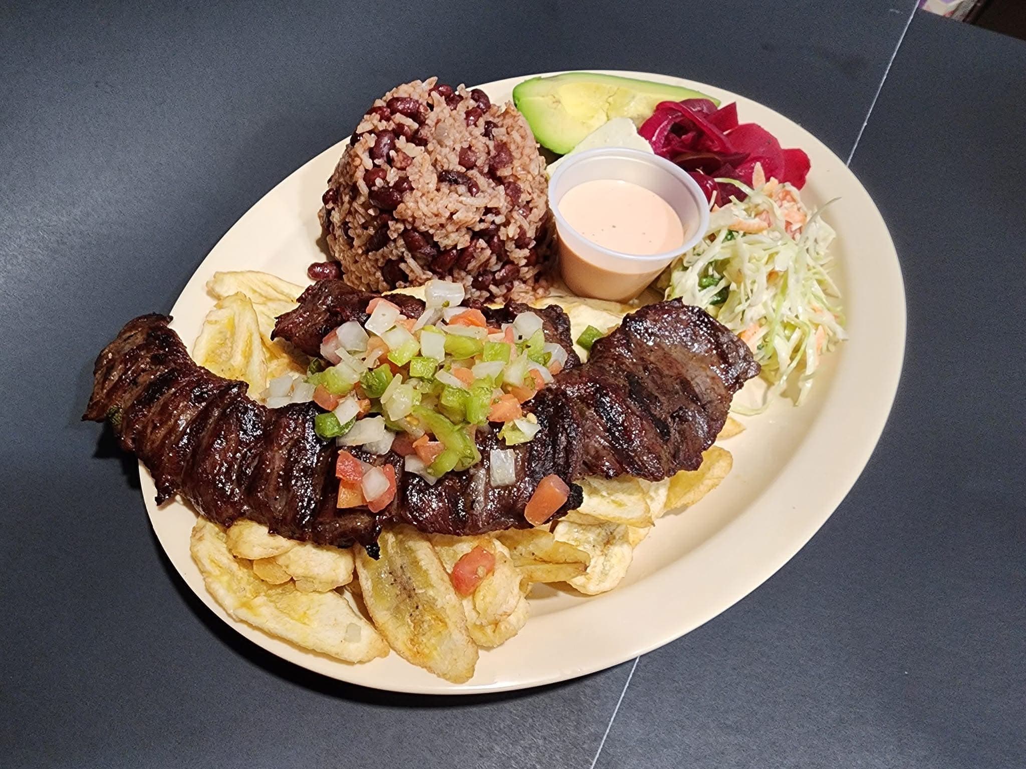Grilled steak with pico de gallo, fried plantains, rice and beans, avocado, and coleslaw.