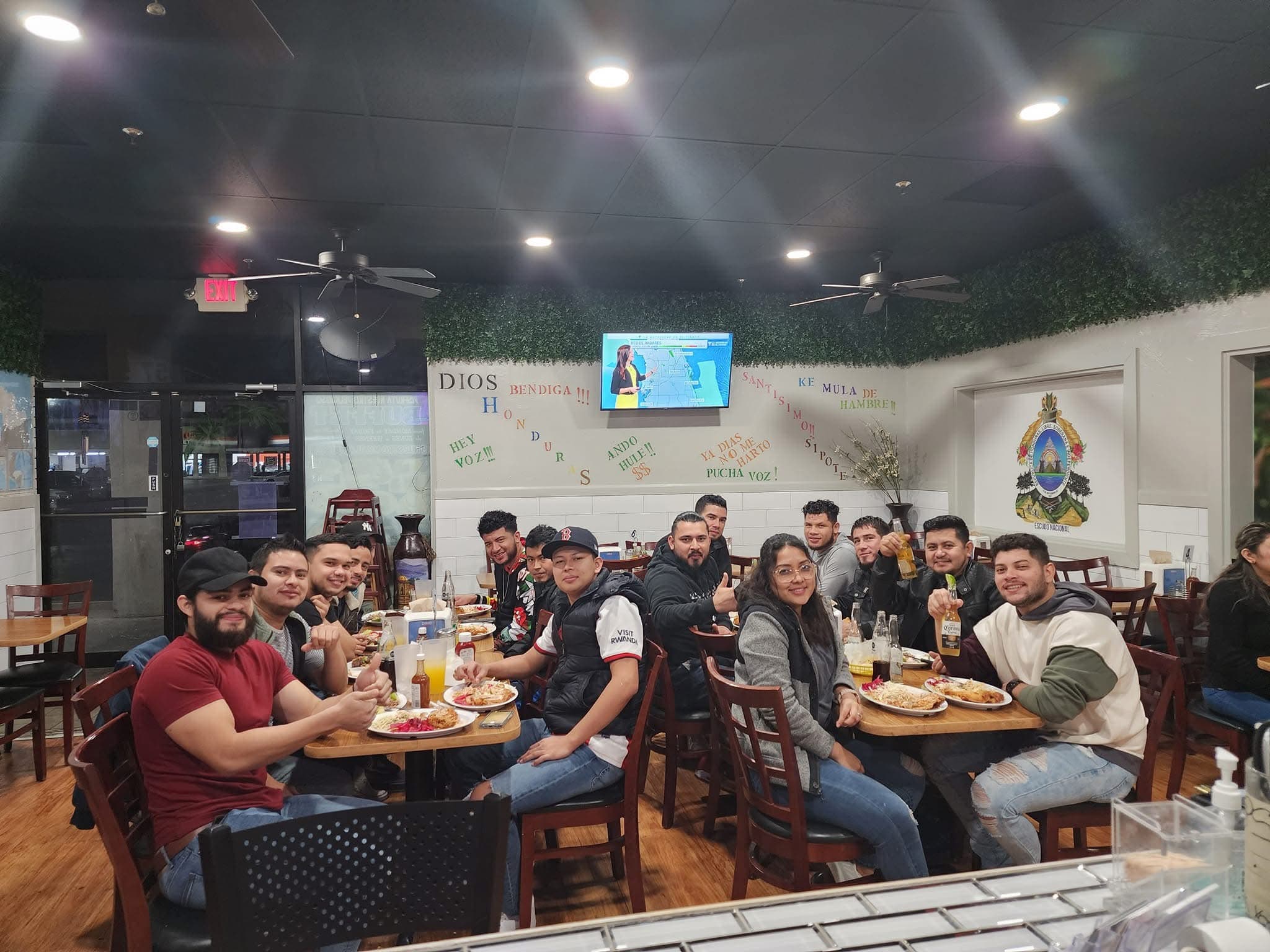 Friends smiling and dining together in a restaurant decorated with Spanish text and art.