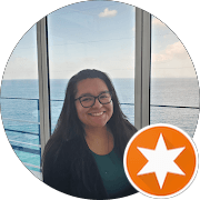 Smiling woman with glasses in front of ocean windows, featuring an orange star badge overlay.